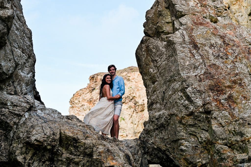 adventurous couple pose on rocks at Perranporth beach