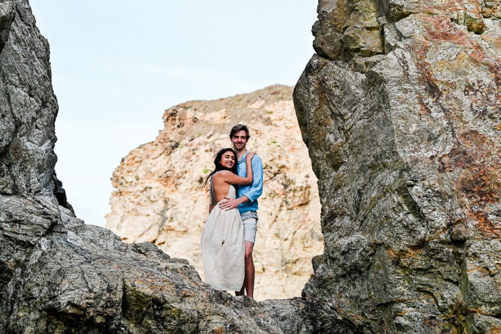 adventurous couple pose on rocks at Perranporth beach