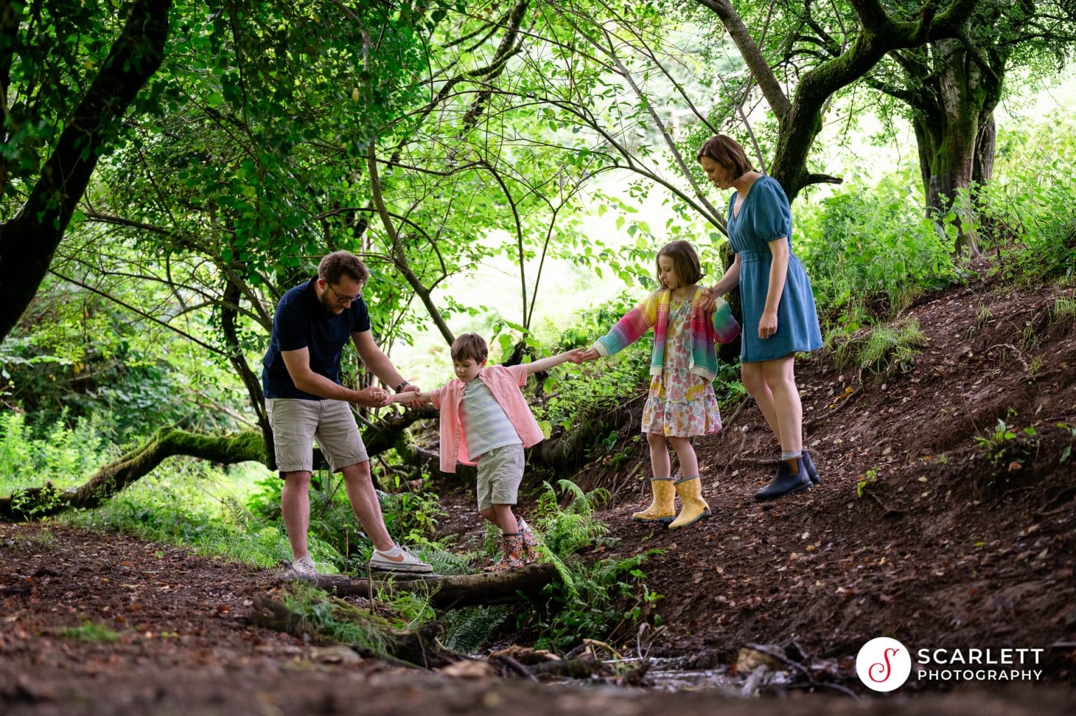 a family help each other down a muddy bank so as not to slip