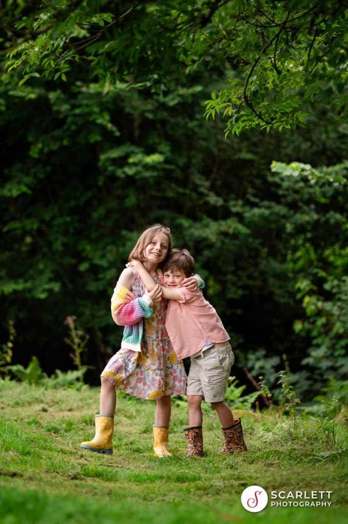 siblings cuddle under a tree on a cornwall family photoshoot