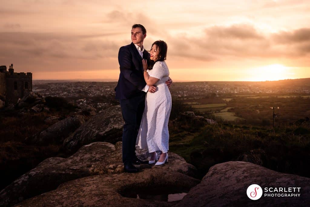 couple pose for a sunrise photoshoot with carn brae in the background