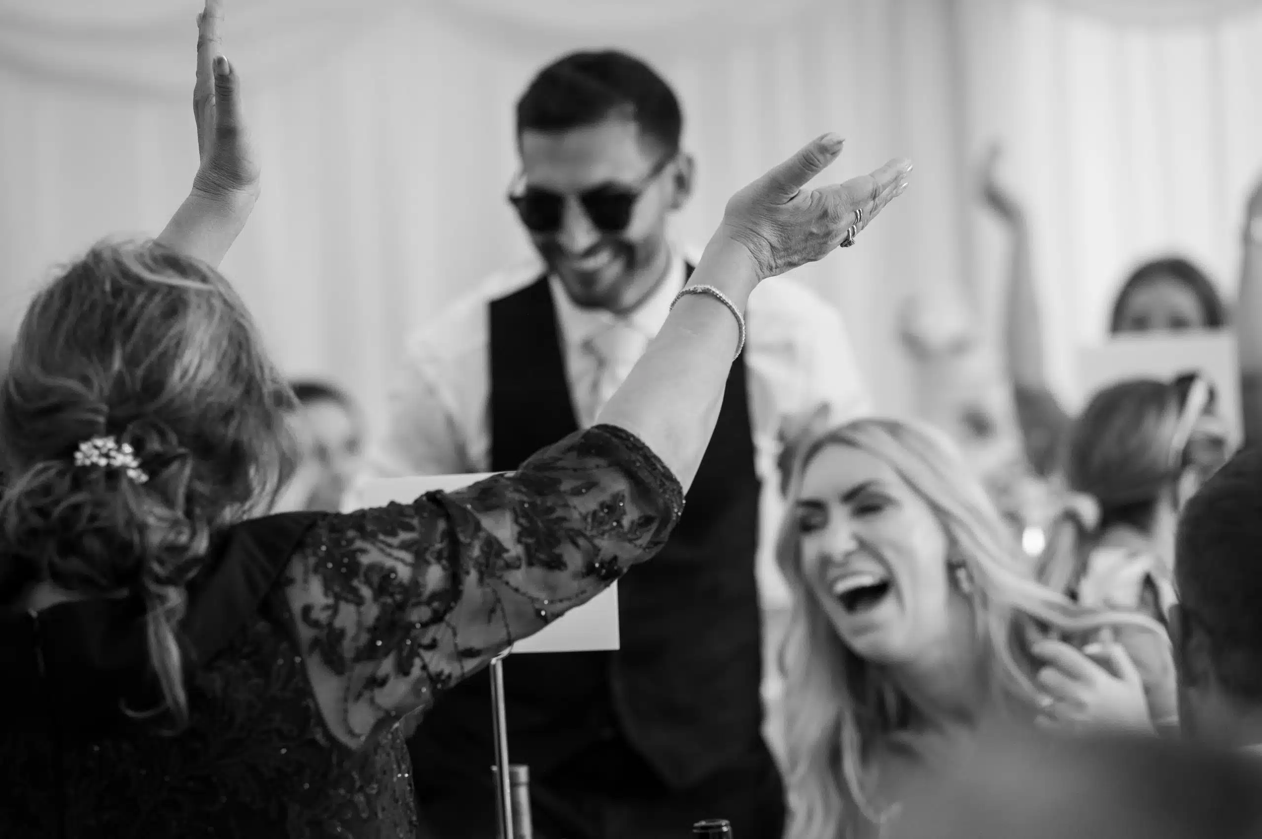 Mother of the groom puts her hands in the air welcoming her new daughter-in-law